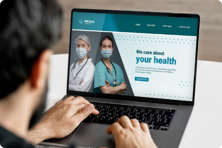 Man viewing a medical website with two masked doctors on a laptop.