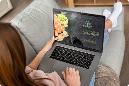 Woman browsing a sushi restaurant website on a laptop.