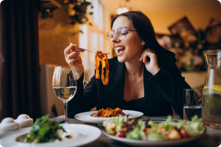 Woman enjoying a pasta meal at a restaurant.