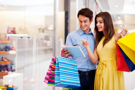 Couple shopping and looking at a tablet in a mall.