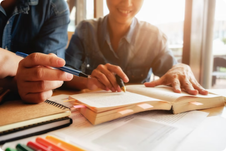 Two people studying together with books and pens.
