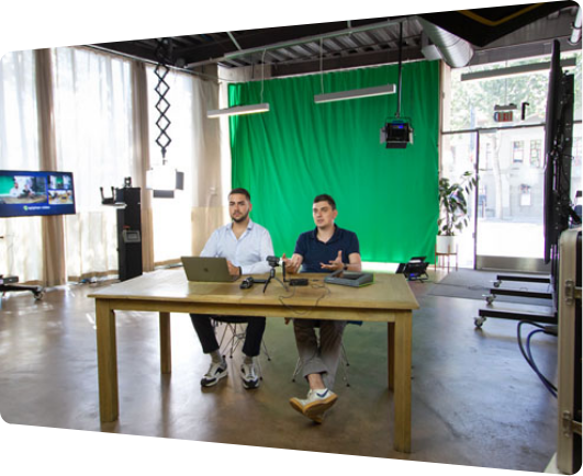 Two men working in a video studio with a green screen.